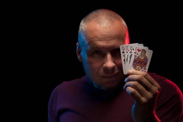 man holds a deck of cards and shows tricks in a scenic light