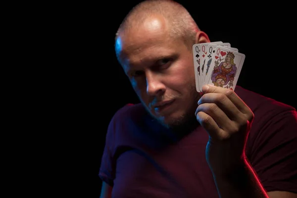 man holds a deck of cards and shows tricks in a scenic light