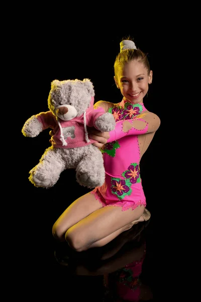 young girl athlete gymnast performs acrobatic elements on a black background