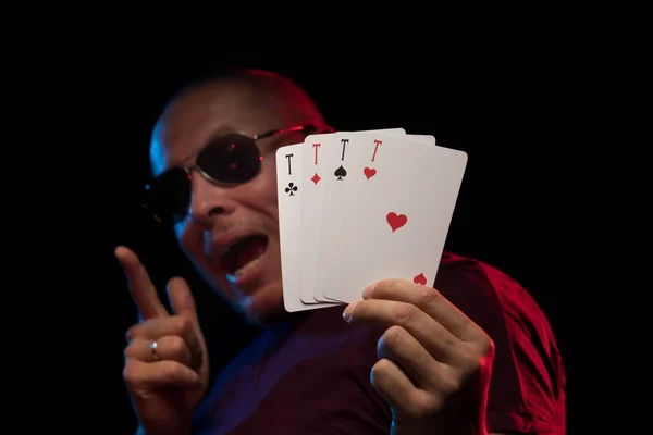 man holds a deck of cards and shows tricks in a scenic light