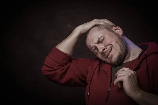 Emotional actor brutal man with a beard in a hood on a black background