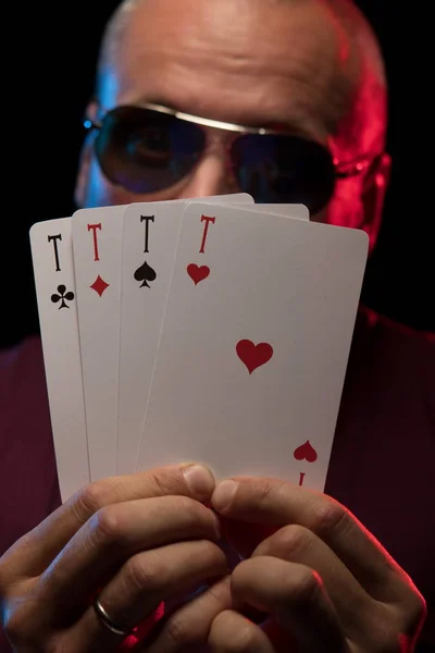 man holds a deck of cards and shows tricks in a scenic light