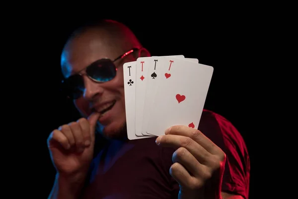 man holds a deck of cards and shows tricks in a scenic light