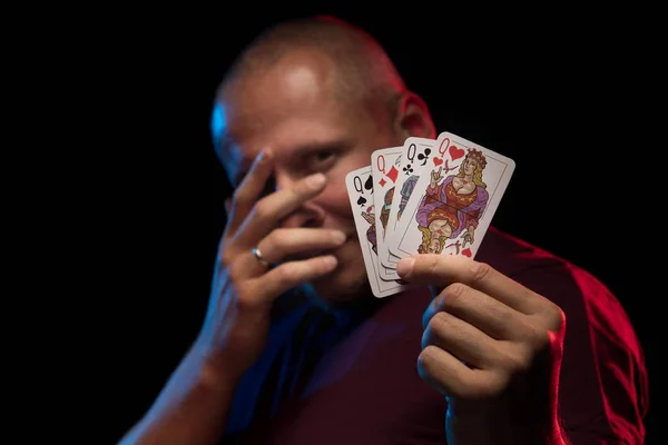 man holds a deck of cards and shows tricks in a scenic light