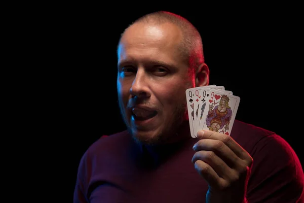 man holds a deck of cards and shows tricks in a scenic light