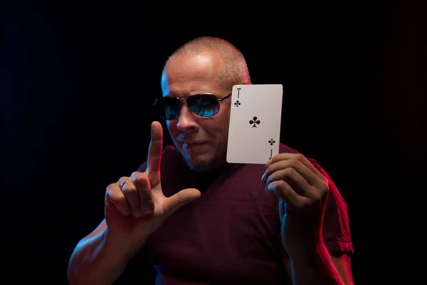 man holds a deck of cards and shows tricks in a scenic light