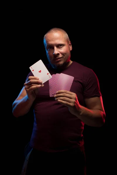 man holds a deck of cards and shows tricks in a scenic light