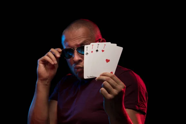 man holds a deck of cards and shows tricks in a scenic light