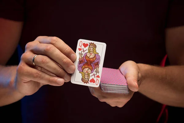 man holds a deck of cards and shows tricks in a scenic light.