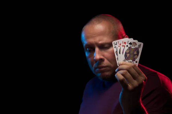 man holds a deck of cards and shows tricks in a scenic light