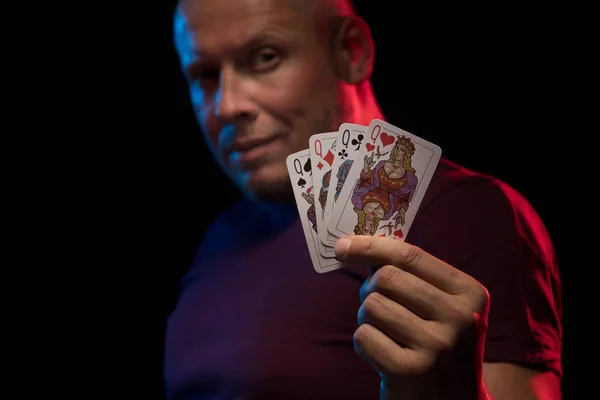 man holds a deck of cards and shows tricks in a scenic light