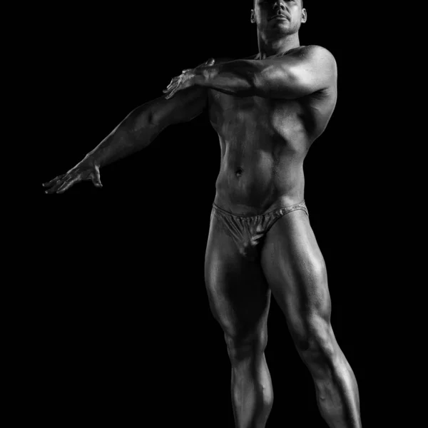 Black and white portrait of male athlete bodybuilder posing on a black background