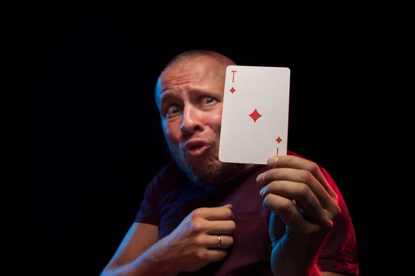 man holds a deck of cards and shows tricks in a scenic light