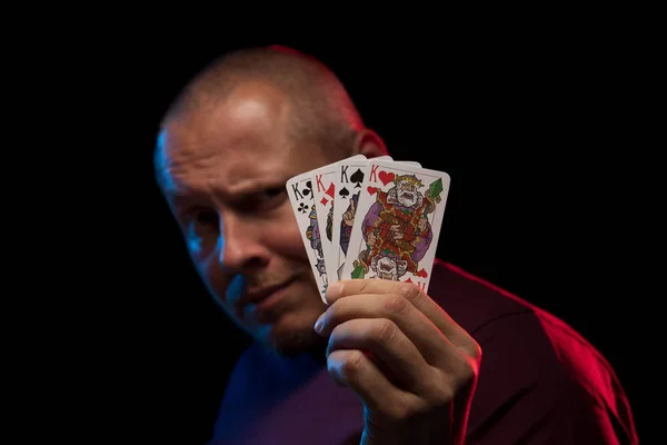 man holds a deck of cards and shows tricks in a scenic light