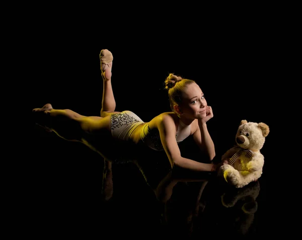 young girl athlete gymnast performs acrobatic elements on a black background