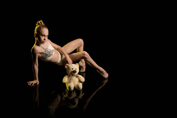 young girl athlete gymnast performs acrobatic elements on a black background