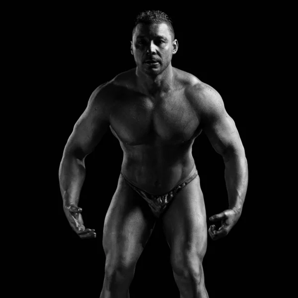 Black and white portrait of male athlete bodybuilder posing on a black background