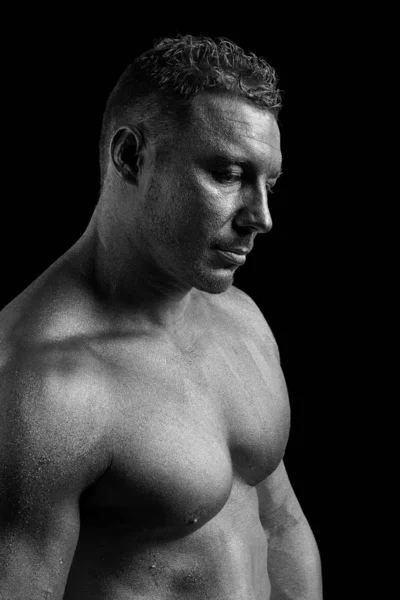 Black and white portrait of male athlete bodybuilder posing on a black background