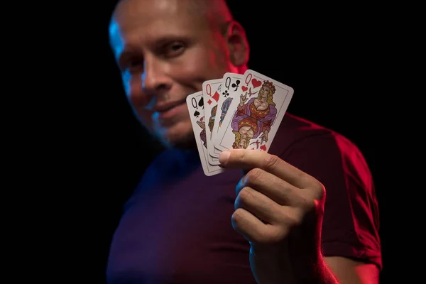 man holds a deck of cards and shows tricks in a scenic light