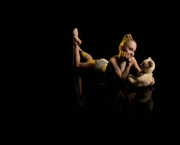 young girl athlete gymnast performs acrobatic elements on a black background