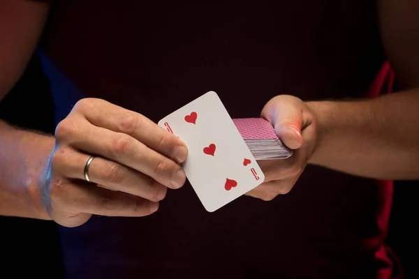 man holds a deck of cards and shows tricks in a scenic light.