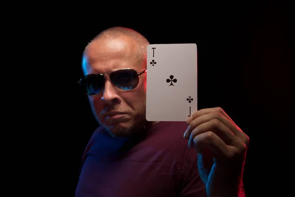 man holds a deck of cards and shows tricks in a scenic light