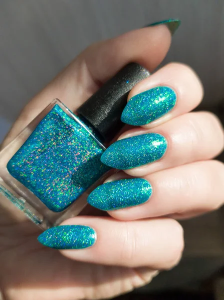Female hand with long nails with bottle with a bright nail polish