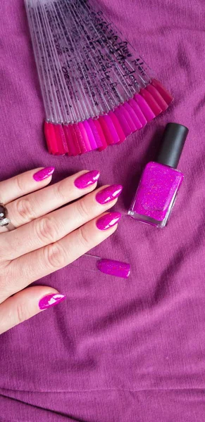 Female hand with long nails with bottle with a bright nail polish