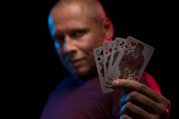 man holds a deck of cards and shows tricks in a scenic light