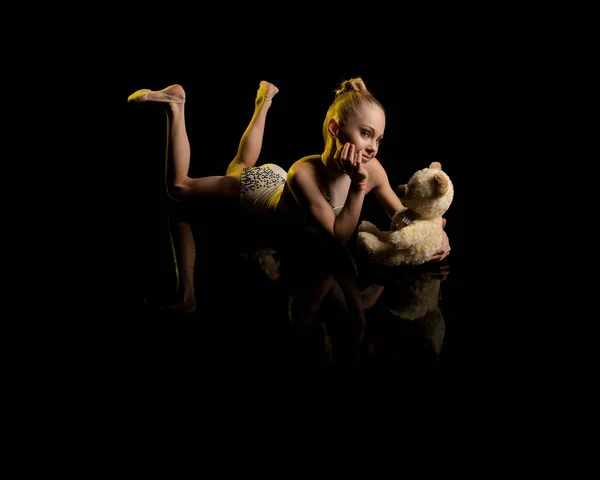 young girl athlete gymnast performs acrobatic elements on a black background