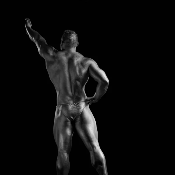 Black and white portrait of male athlete bodybuilder posing on a black background