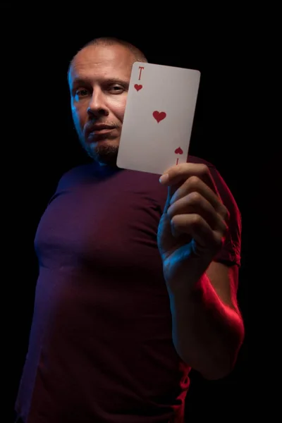 man holds a deck of cards and shows tricks in a scenic light