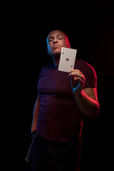 man holds a deck of cards and shows tricks in a scenic light