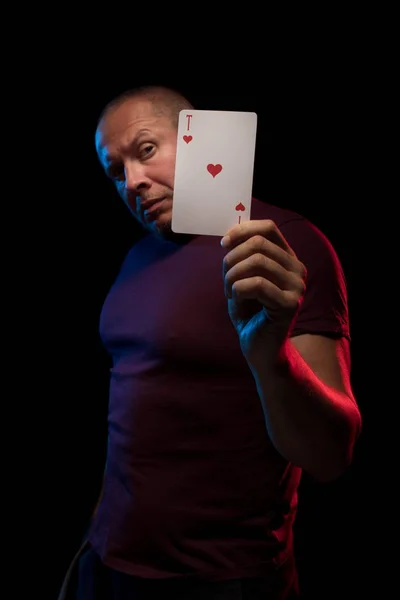 man holds a deck of cards and shows tricks in a scenic light