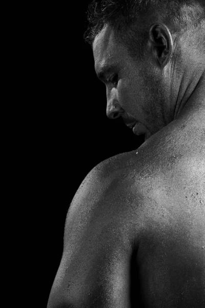 Black and white portrait of male athlete bodybuilder posing on a black background