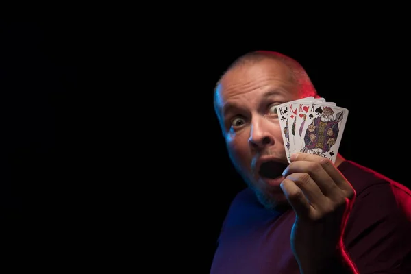 man holds a deck of cards and shows tricks in a scenic light