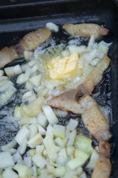 meat, onions  fried in a pan on a fire in the forest