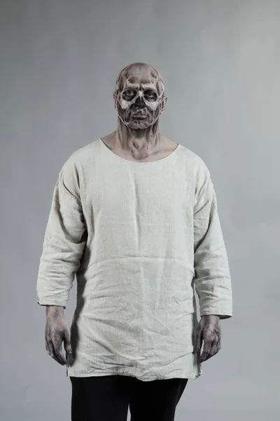 Male actor in zombie viking make up and costume posing on grey background