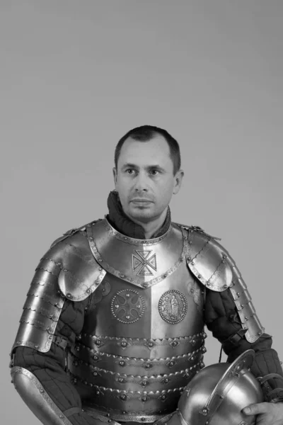 Man in armor of hussar legion posing on gray background. Black and white photo