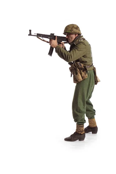 Man actor in the movie role of an old military man with a machine gun posing against white background