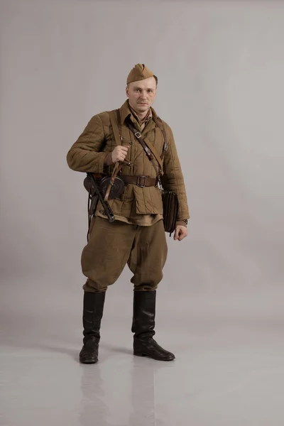 Male actor in the form of ordinary soldiers of the Russian army in the period 1939-1940, with the Tokarev Self-loading rifle on a white background in the studio