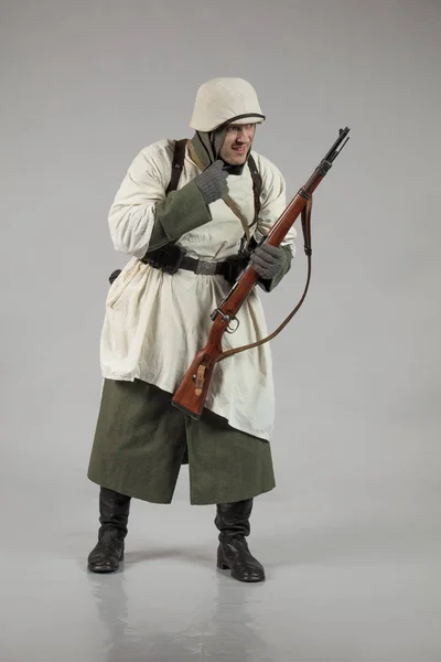 male actor movie in the role in the winter military uniform of an old soldier, the period 1942, the Second World War, posing on a gray background