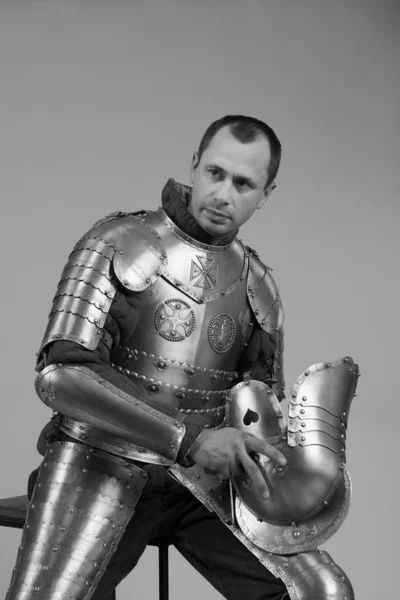 Man in armor of hussar legion posing on gray background. Black and white photo