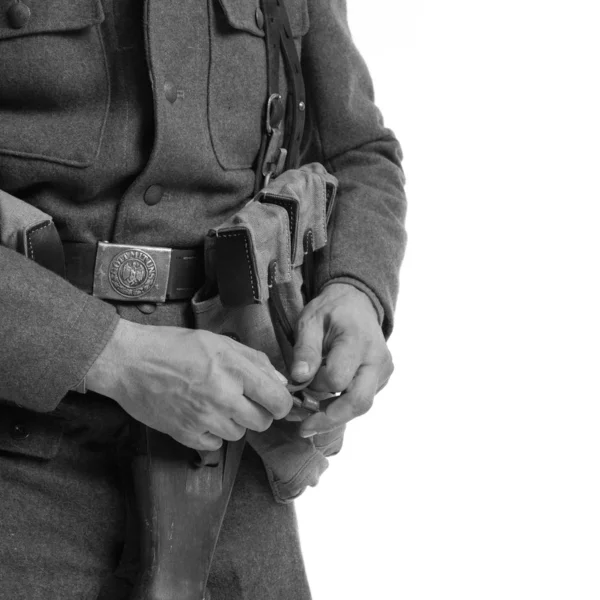 Man actor in the movie role of an old military man with a machine gun posing against white background