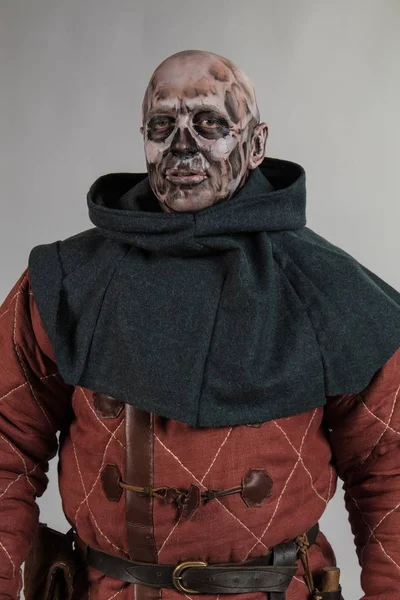 Male actor in zombie viking make up and costume posing on grey background