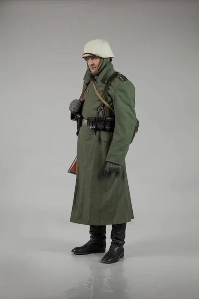 male actor movie in the role in the winter military uniform of an old soldier, the period 1942, the Second World War, posing on a gray background