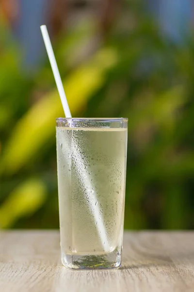 Transparent misted glass with water and straw on table outdoors