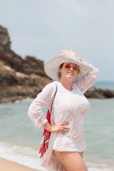 woman in a white hat posing in the sea on a beach background