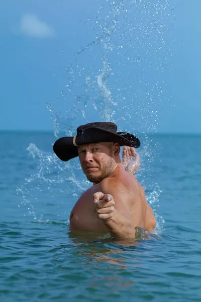Emotional man in a black hat pirate posing on the beach