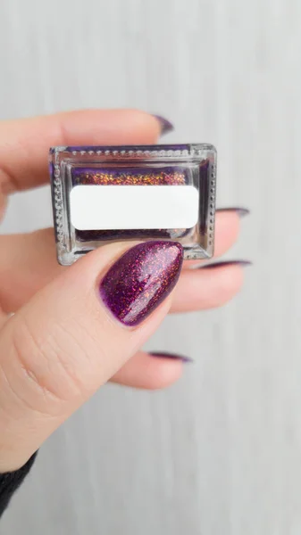 Female hand with long nails with purple nail polish